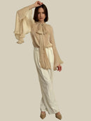 Beige skjorta med långa utsvängda ärmar och rosett i halsen