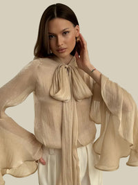 Beige skjorta med långa utsvängda ärmar och rosett i halsen