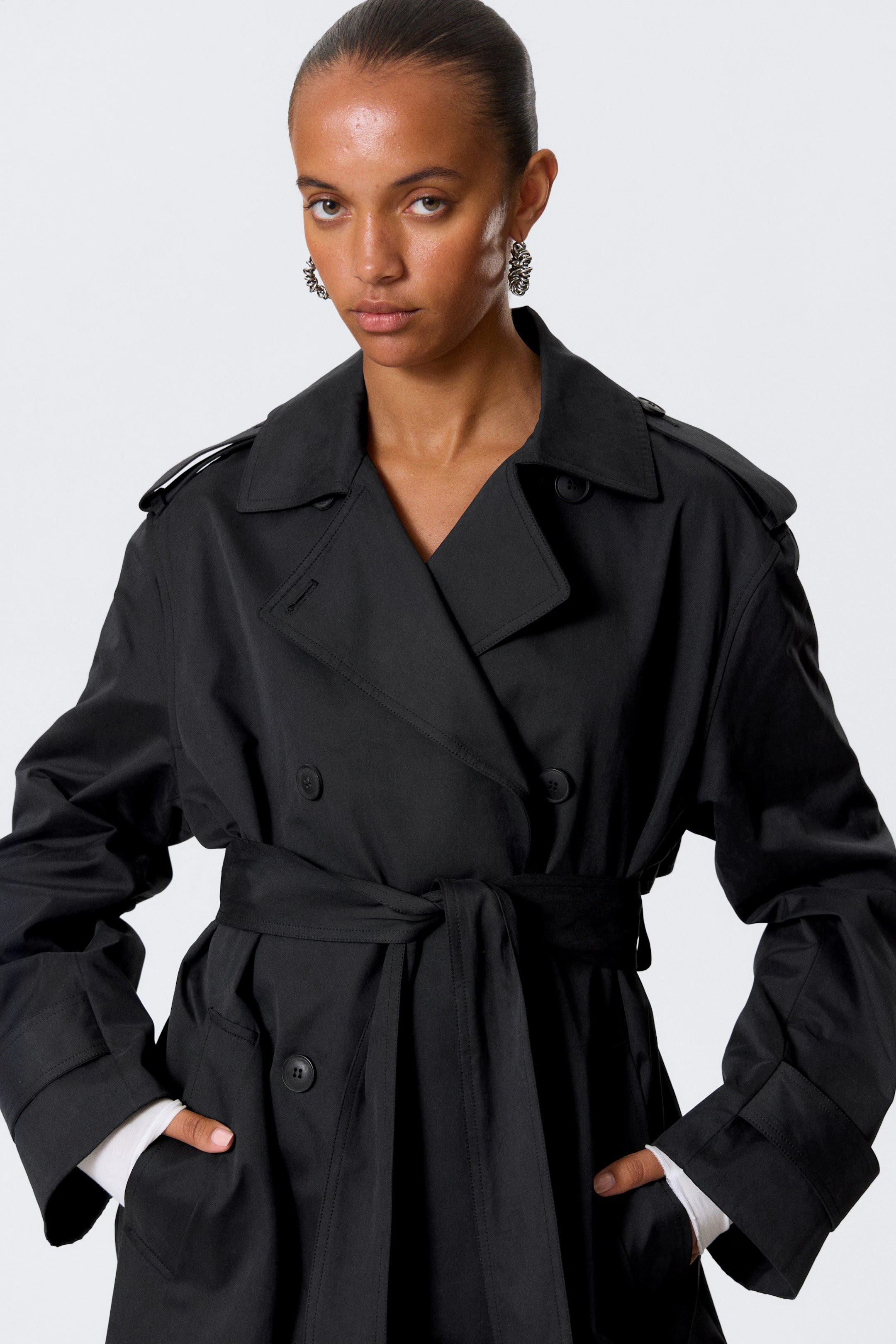 Svart trenchcoat med knappar och bälte