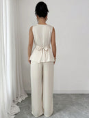 Vit kostym med blus med vågor i ändarna och utsvängda byxor