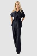 Tvådelad kostym med utsvängda byxor och blus med knappar